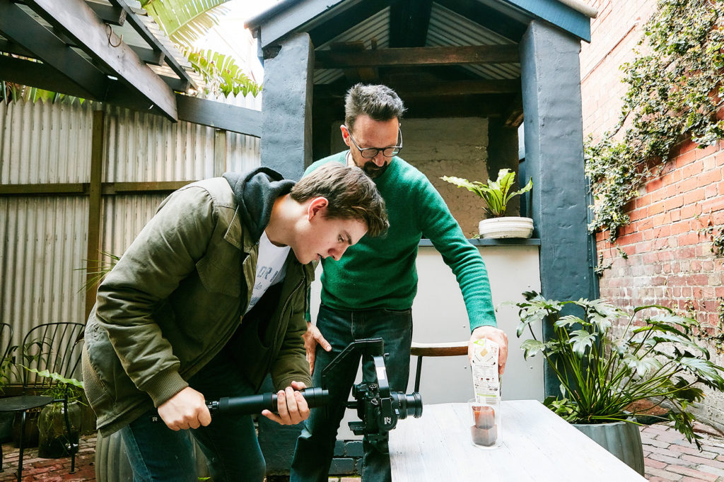 Two alumni film a video together in a courtyard setting