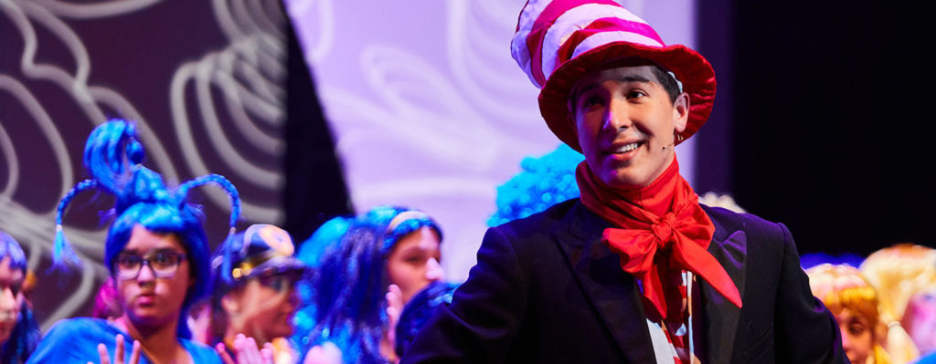 A Luther College student plays the Cat in the Hat, with other students performing in the background